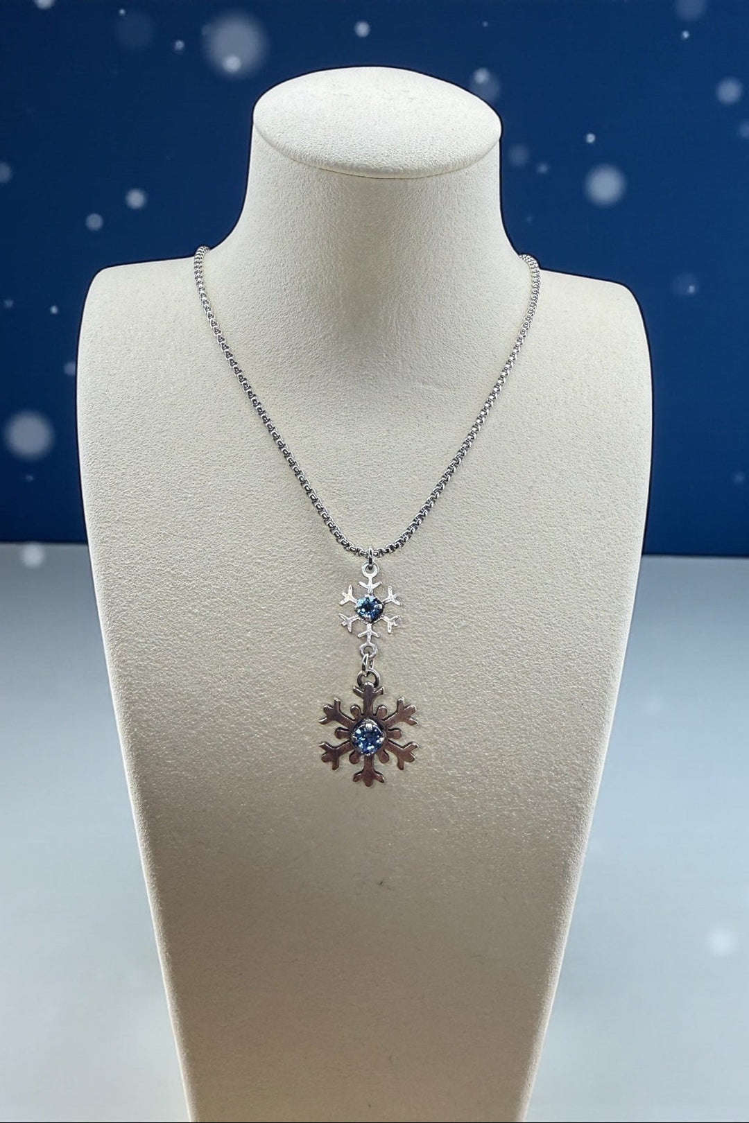Necklace with a snowflake and crystal pendant on a mannequin bust against a snowy background